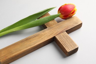 Photo of Easter - celebration of Jesus resurrection. Wooden cross and tulip on light background, closeup