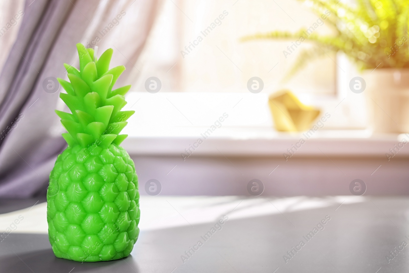 Photo of Pineapple shaped candle on table in room