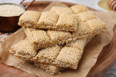 Photo of Wooden tray with delicious sweet kozinaki bars and sesame seeds on white table, closeup