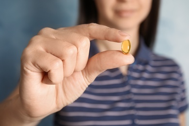 Photo of Woman with cod liver oil pill, closeup