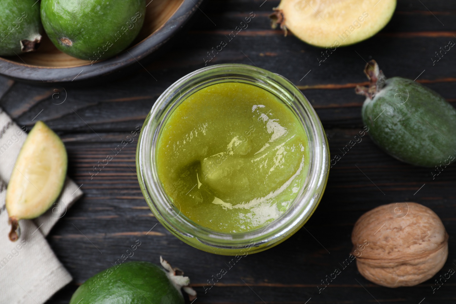 Photo of Feijoa jam and fresh fruits on black wooden table, flat lay