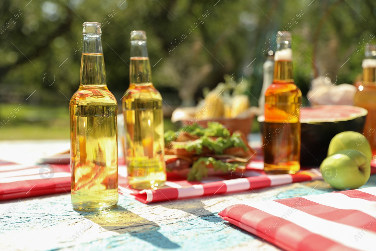 Photo of Different products and drinks for summer picnic served on checkered blanket outdoors
