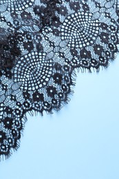 Black lace on light blue background, top view. Space for text