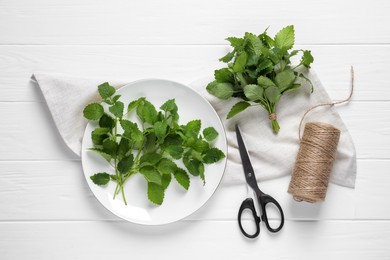 Fresh lemon balm, scissors and twine on white wooden table, flat lay