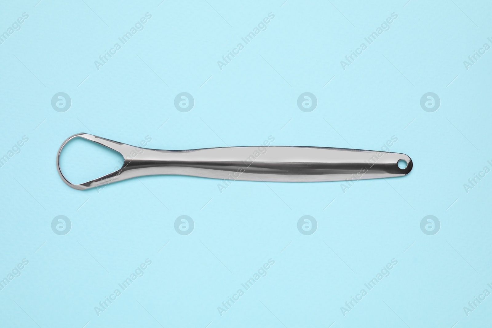 Photo of Metal tongue cleaner on light blue background, top view