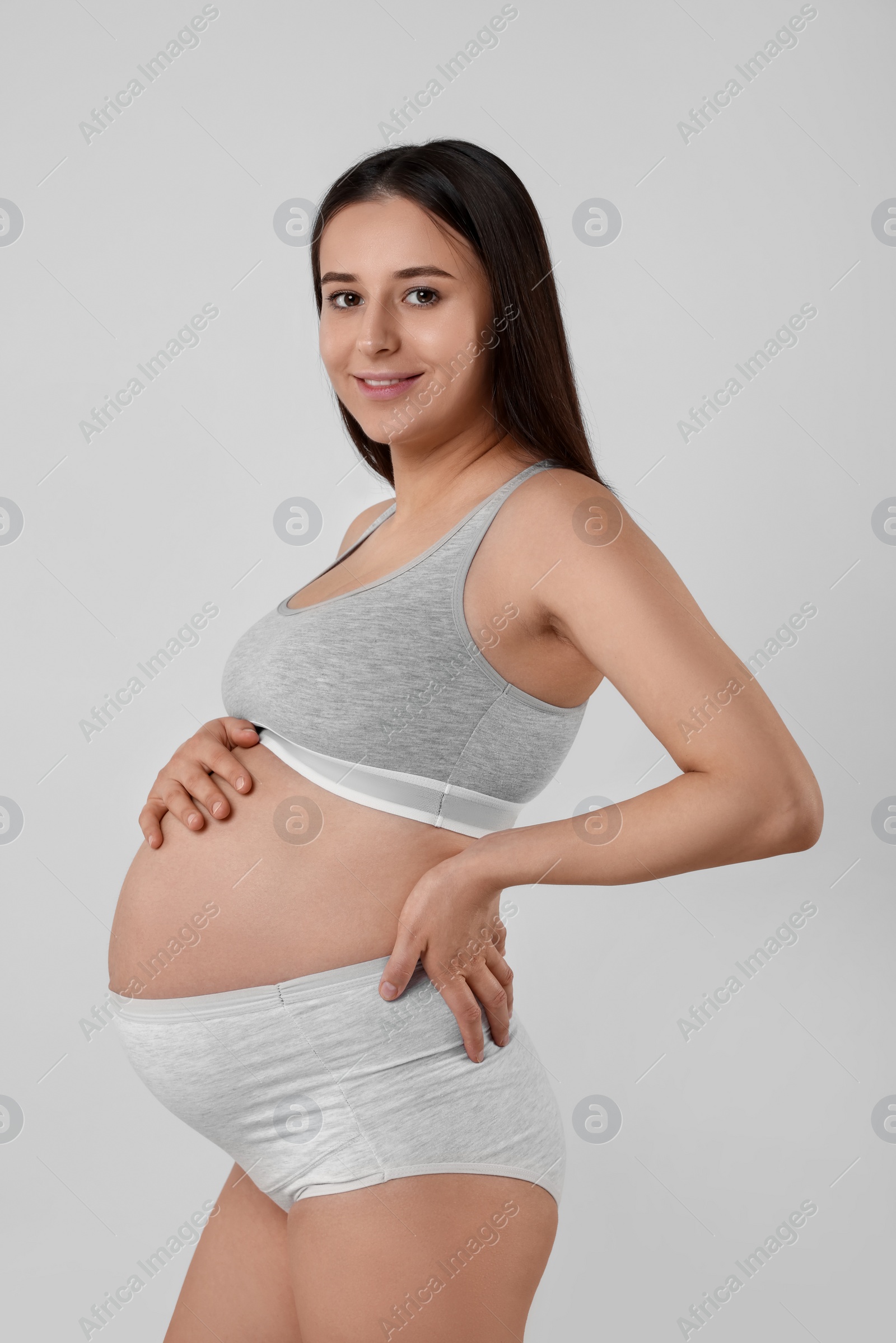 Photo of Beautiful pregnant woman in comfortable maternity underwear on grey background