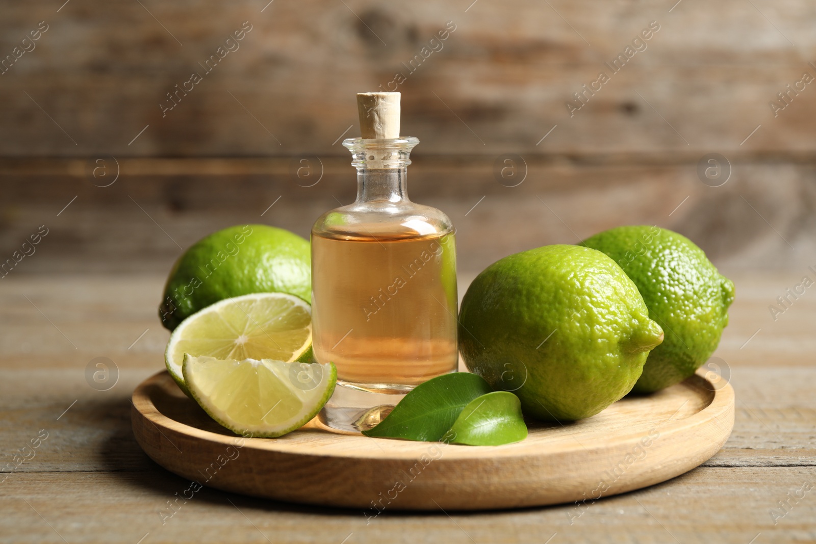 Photo of Lime essential oil and citrus fruits on wooden table