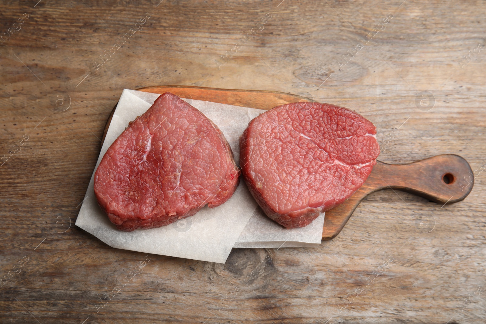 Photo of Fresh raw beef cut on wooden table, top view