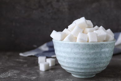 Photo of Refined sugar cubes in bowl on grey table