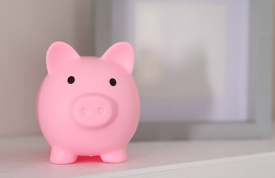 Photo of Pink piggy bank on white table, space for text