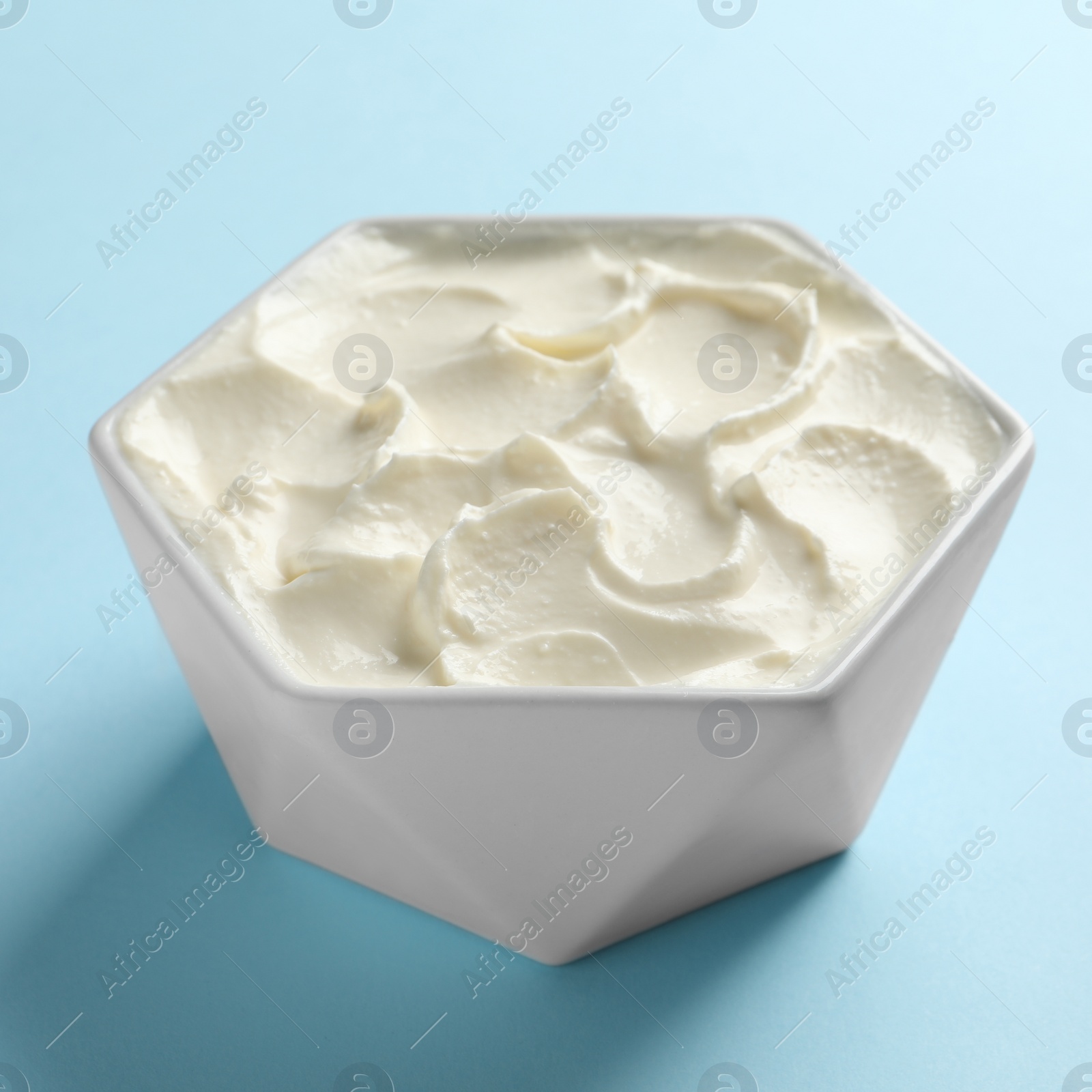 Photo of Bowl of tasty cream cheese on color background