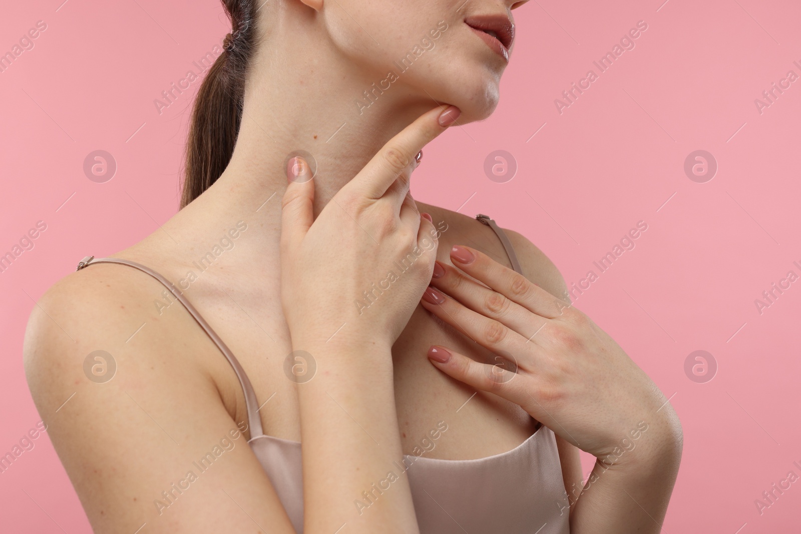 Photo of Woman touching her neck on pink background, closeup