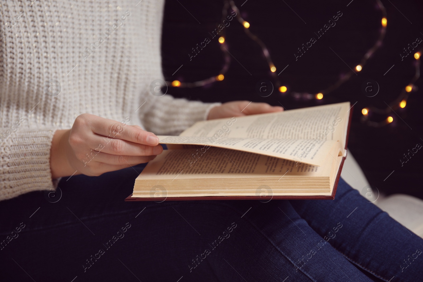 Photo of Young woman reading book at home, closeup