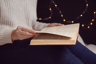 Young woman reading book at home, closeup