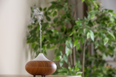 Photo of Aroma oil diffuser lamp on table against blurred background