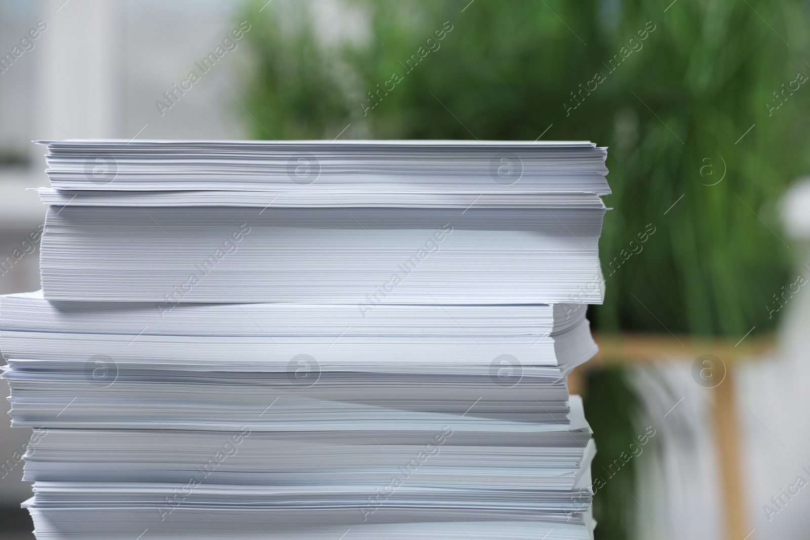 Photo of Stack of paper sheets against blurred background, closeup. Space for text