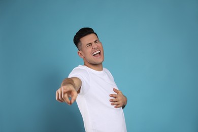 Photo of Handsome man laughing on light blue background. Funny joke