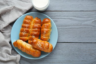 Photo of Delicious sausage rolls and milk on grey wooden table, flat lay. Space for text