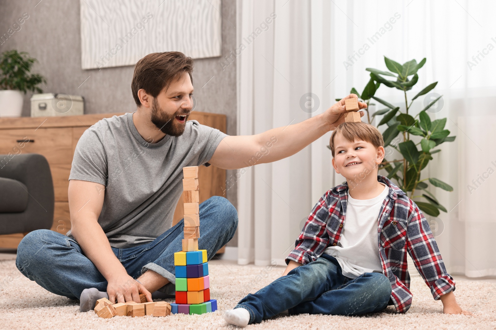 Photo of Happy dad and son having fun with building cubes at home