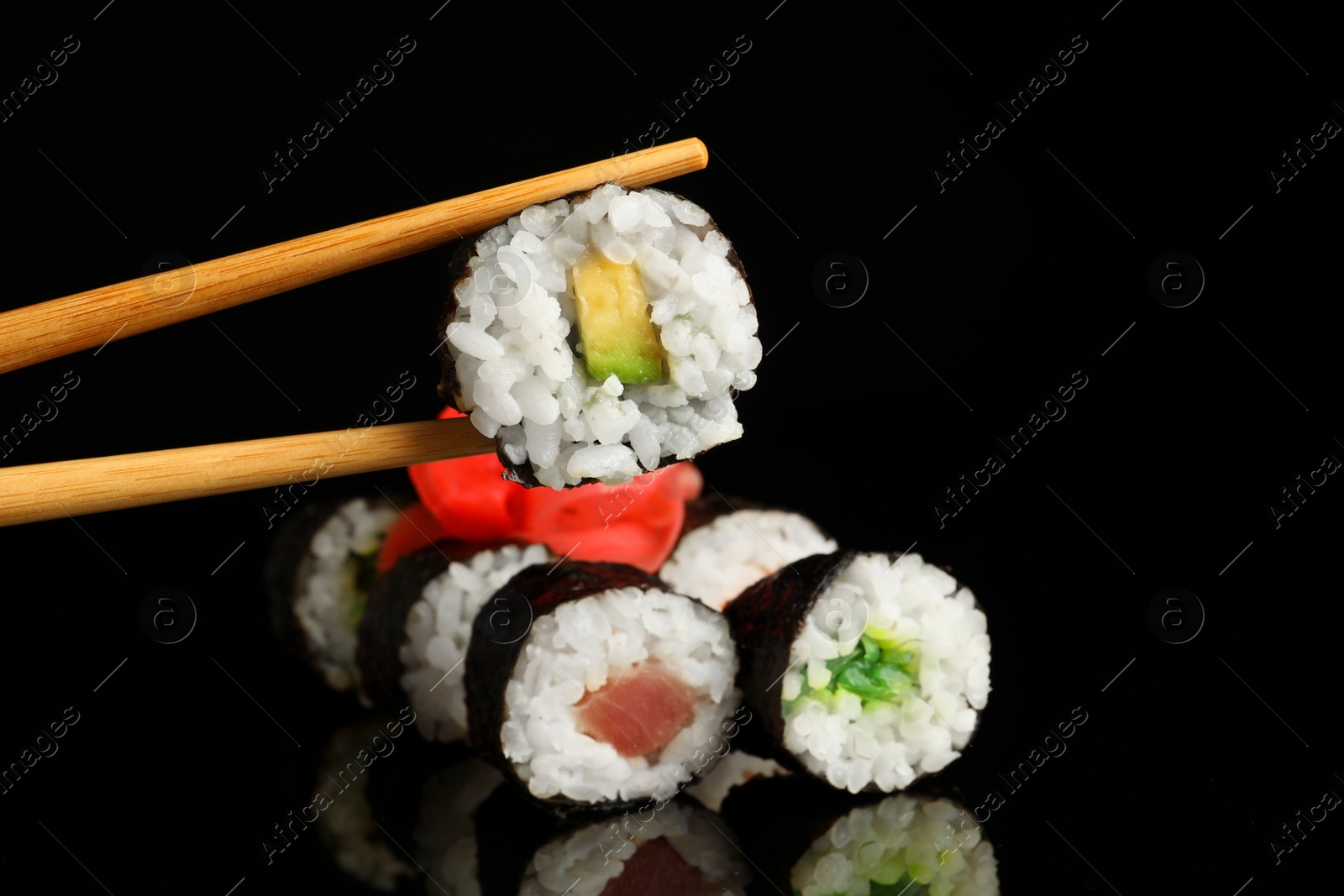 Photo of Set of delicious sushi rolls and chopsticks on black background
