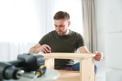 Photo of Young working man using measure tape at home