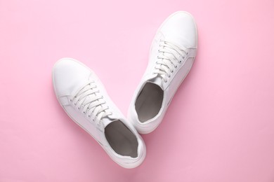 Photo of Pair of stylish white sneakers on pink background, top view