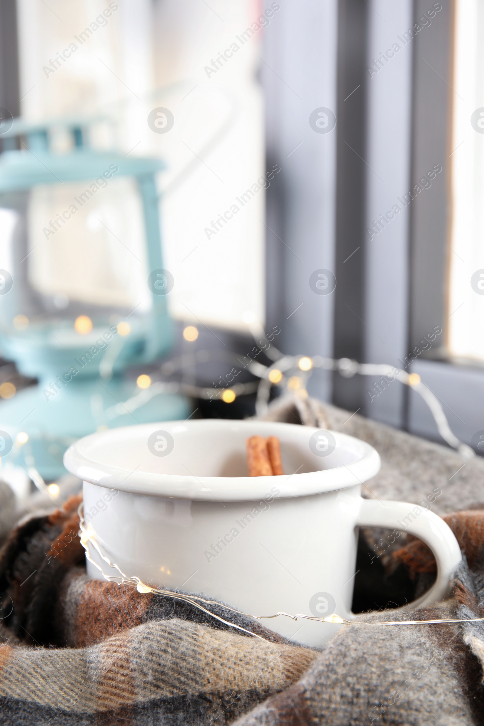 Photo of Composition with cup of hot winter drink, scarf and Christmas lights near window. Cozy season