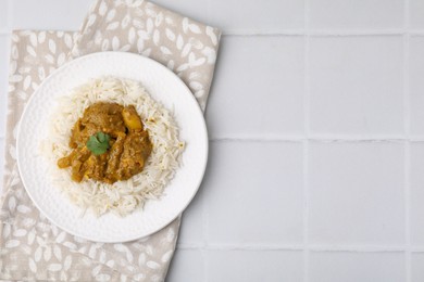 Photo of Delicious chicken curry with rice on white tiled table, top view. Space for text