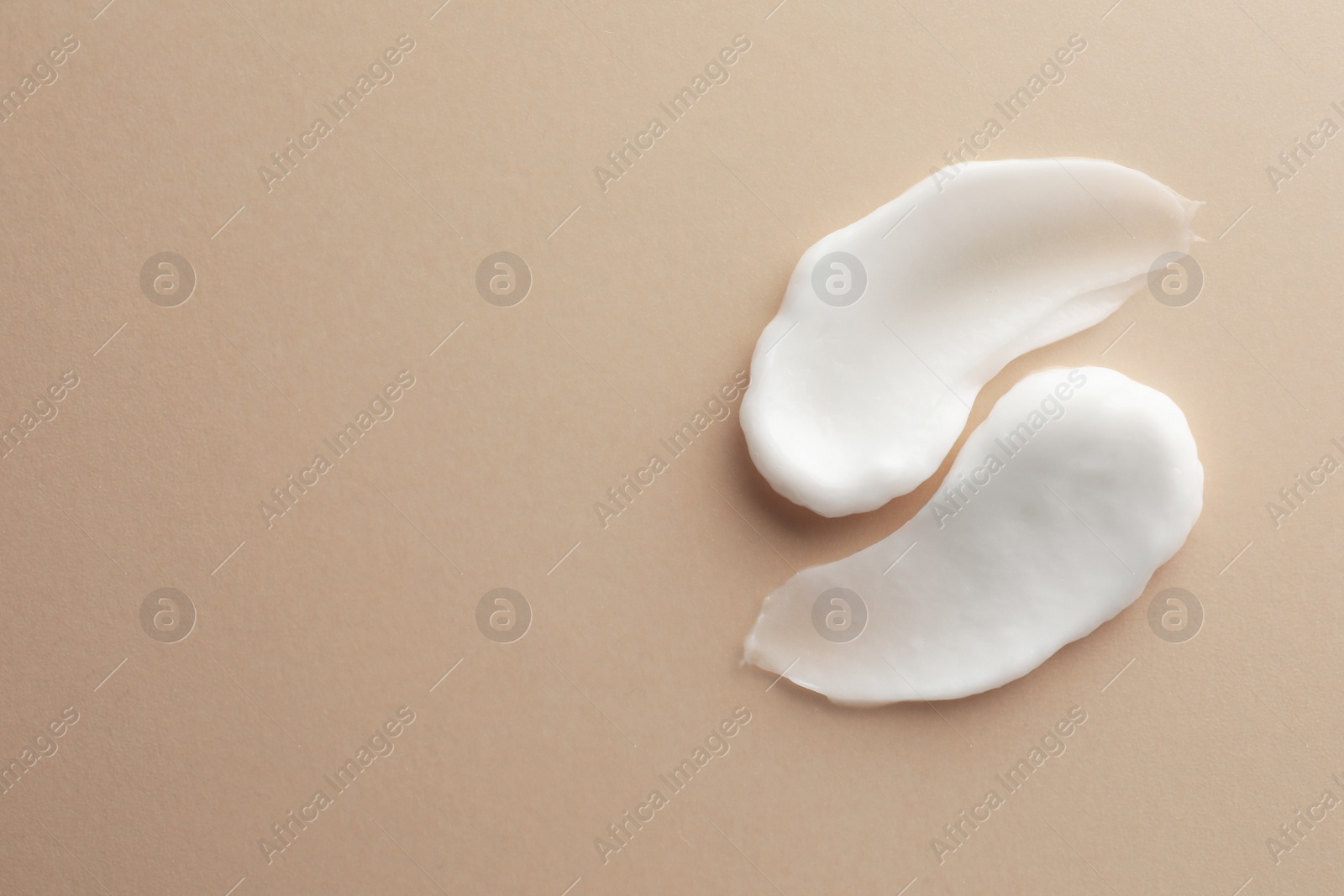 Photo of Sample facial cream on beige background, top view. Space for text