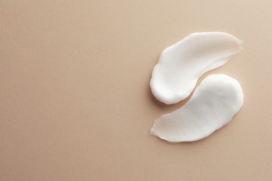 Photo of Sample facial cream on beige background, top view. Space for text