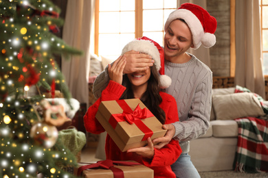 Image of Happy couple with gift boxes in living room decorated for Christmas