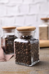 Glass jars with peppercorns on wooden table
