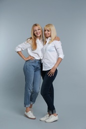 Photo of Portrait of young woman with her mature mother on grey background