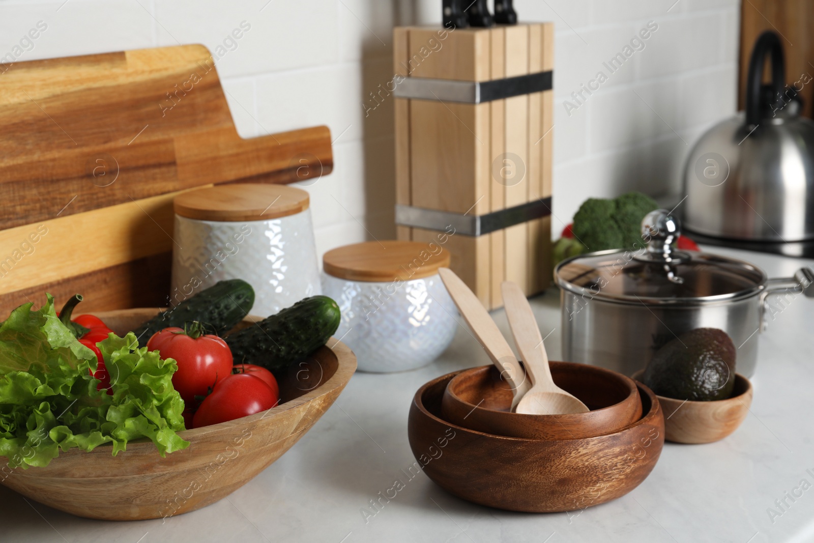 Photo of Different cooking utensils and fresh vegetables on countertop in kitchen