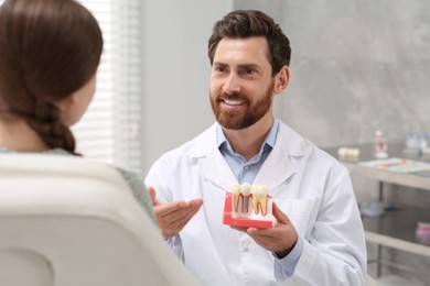 Photo of Doctor with educational model of dental implant consulting patient in clinic