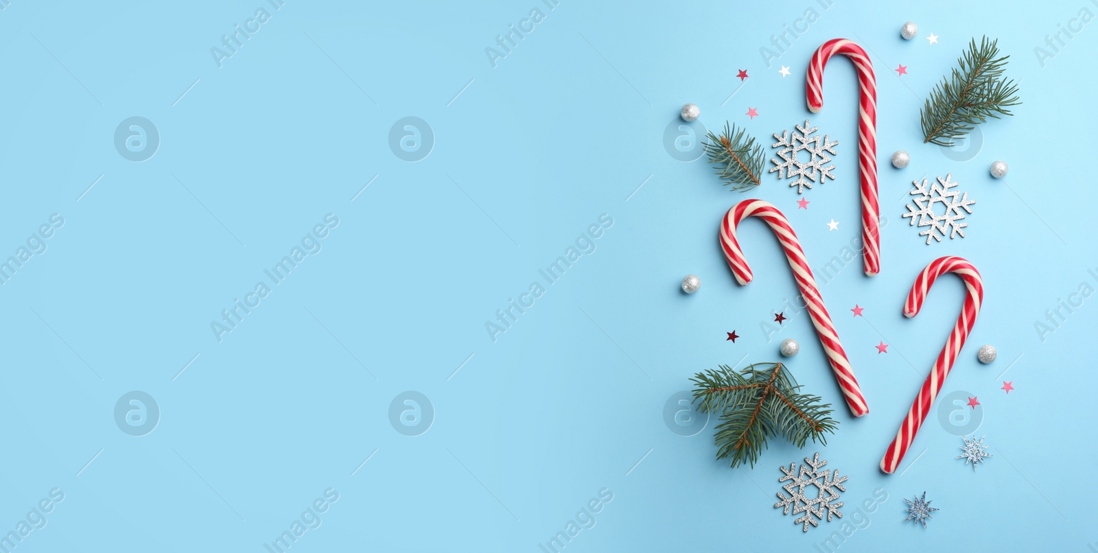 Photo of Flat lay composition with candy canes and Christmas decor on light blue background