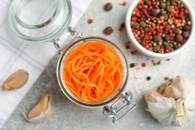 Delicious Korean carrot salad, garlic and spices on grey table, flat lay