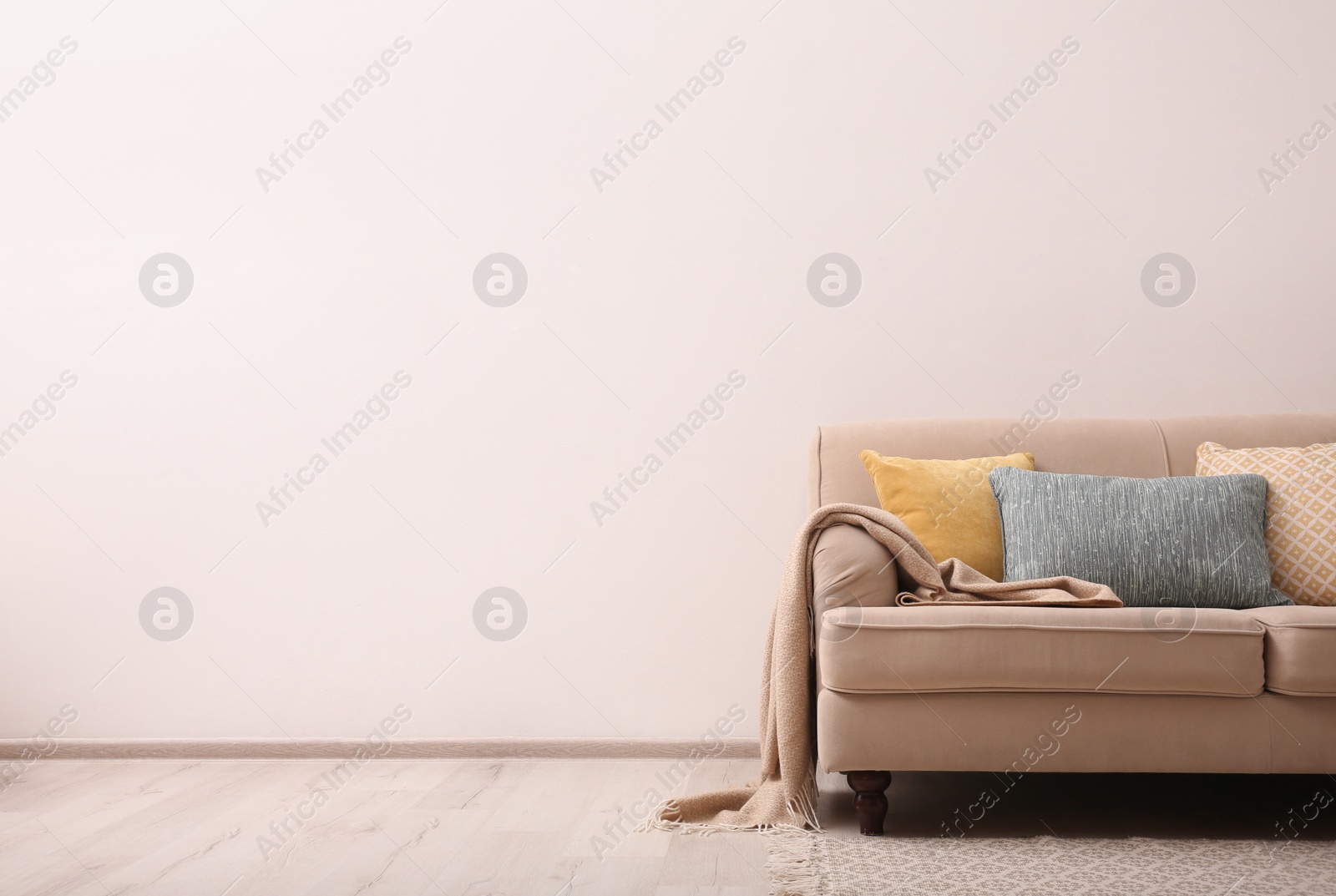 Photo of Comfortable beige sofa near light wall indoors, space for text. Simple interior