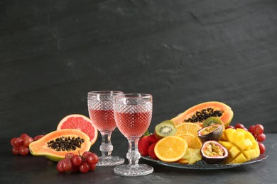 Delicious exotic fruits and glasses of wine on black table