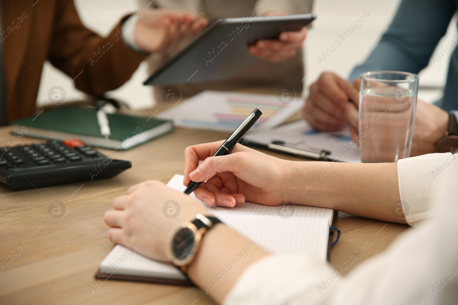 Photo of Woman writing in notebook at table during business meeting, closeup. Management consulting