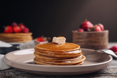 Tasty pancakes with butter and honey on wooden table, closeup