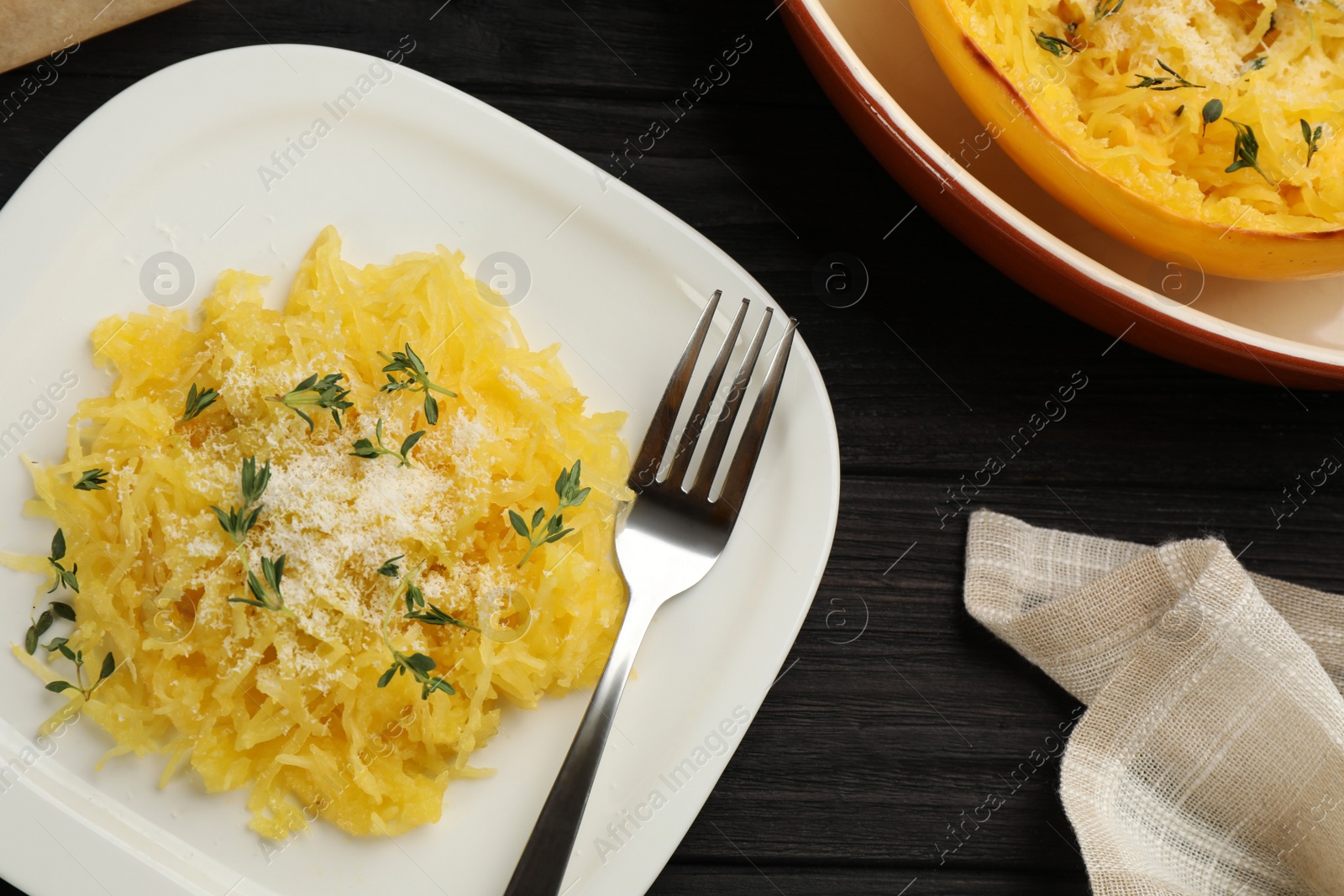 Photo of Tasty spaghetti squash with cheese and thyme served on black wooden table, flat lay