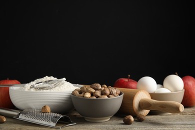 Nutmeg seeds and other ingredients for pastry on wooden table against black background