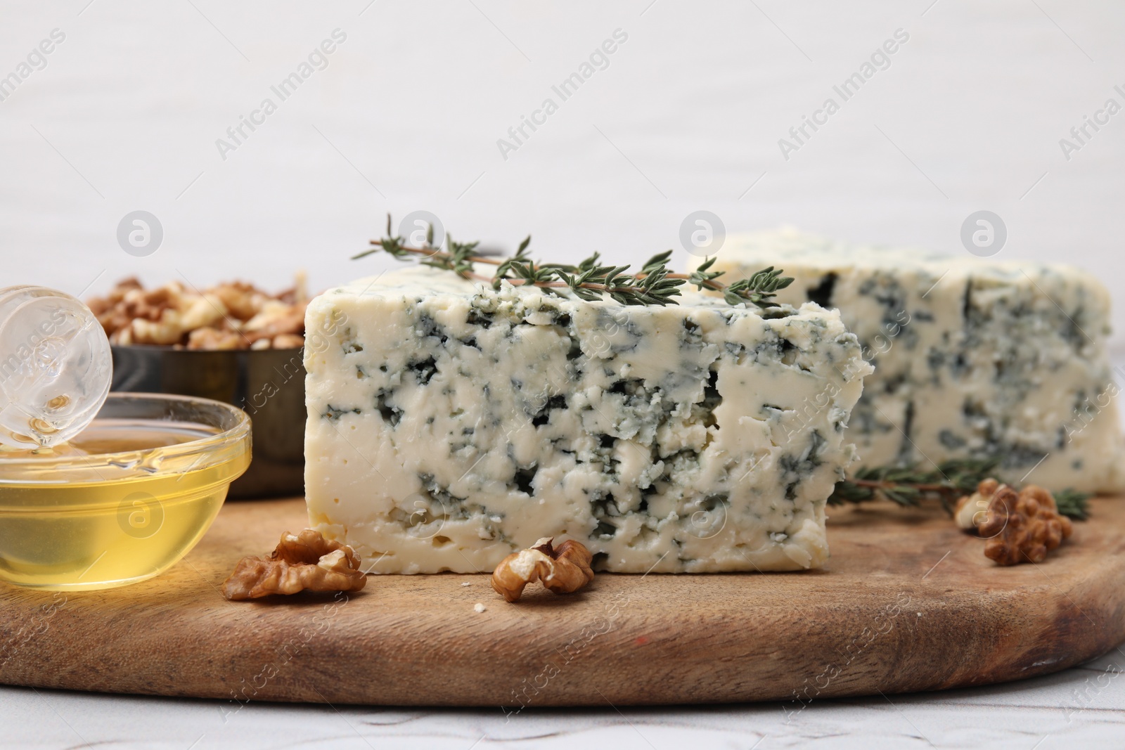 Photo of Tasty blue cheese with thyme, honey and walnuts on white table, closeup