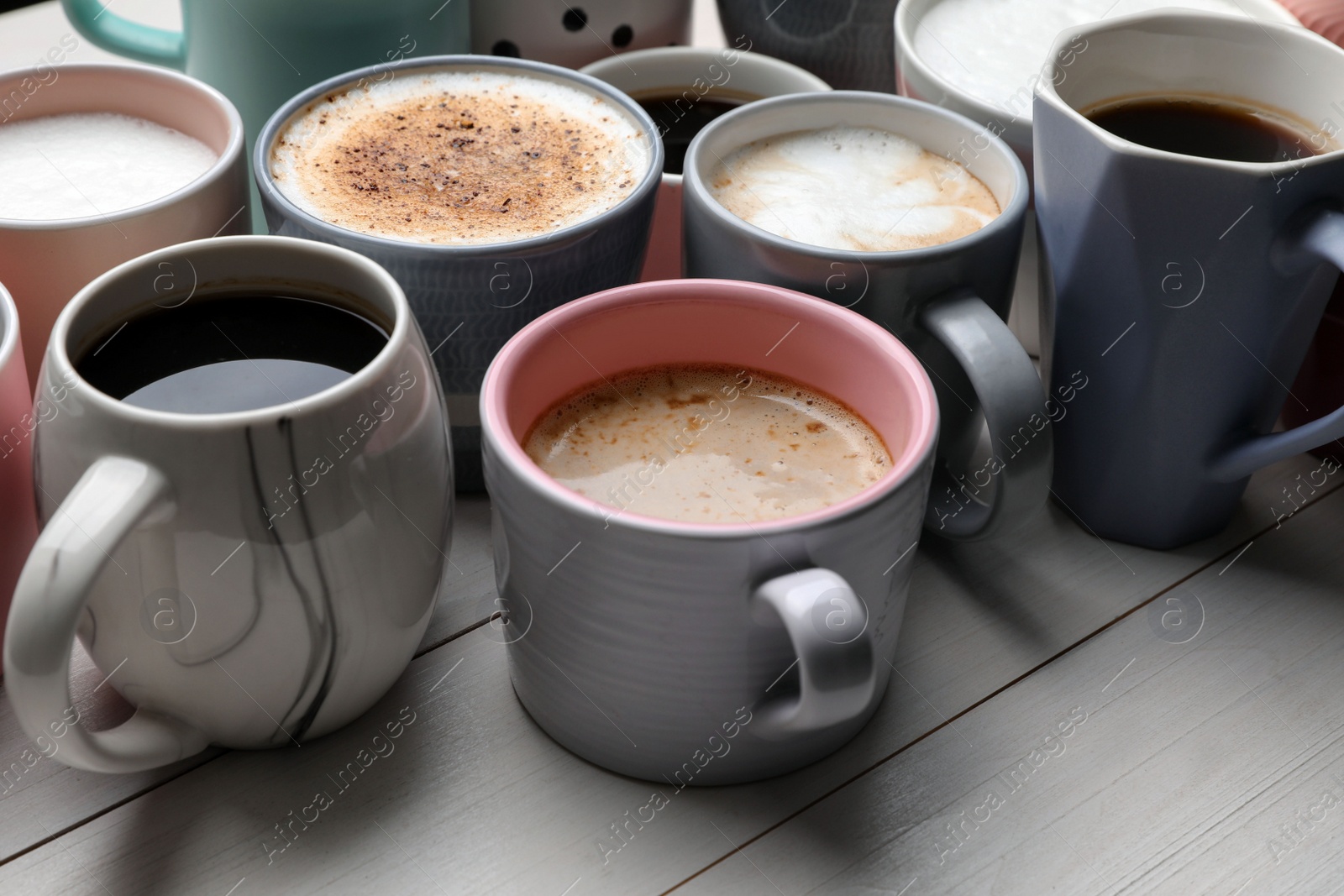 Photo of Many different cups with aromatic hot coffee on white wooden table