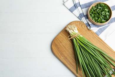 Photo of Fresh green spring onions on white wooden table, flat lay. Space for text