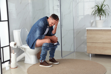 Photo of Man suffering from hemorrhoid on toilet bowl in rest room