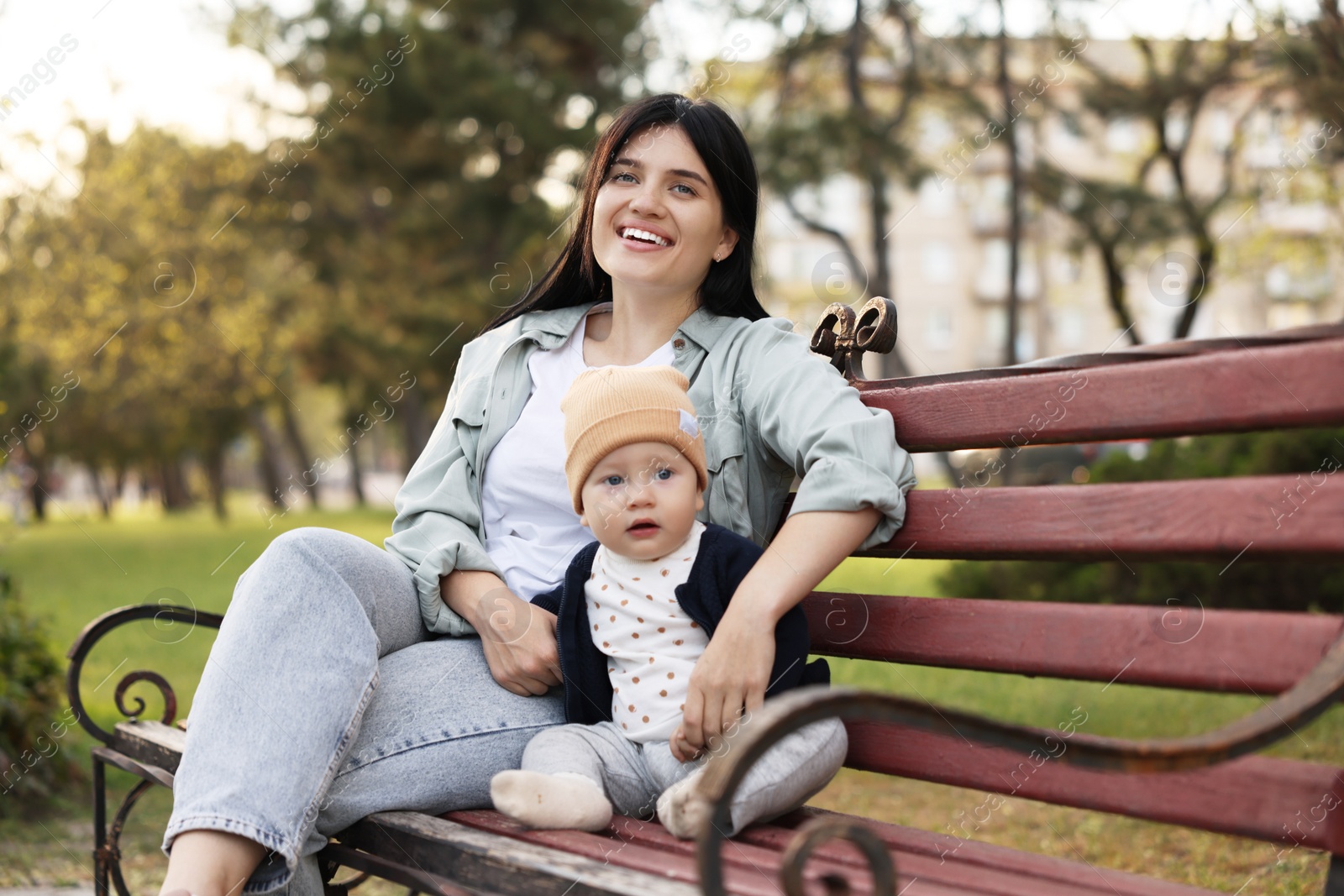 Photo of Family portrait of happy mother and her baby on bench in park