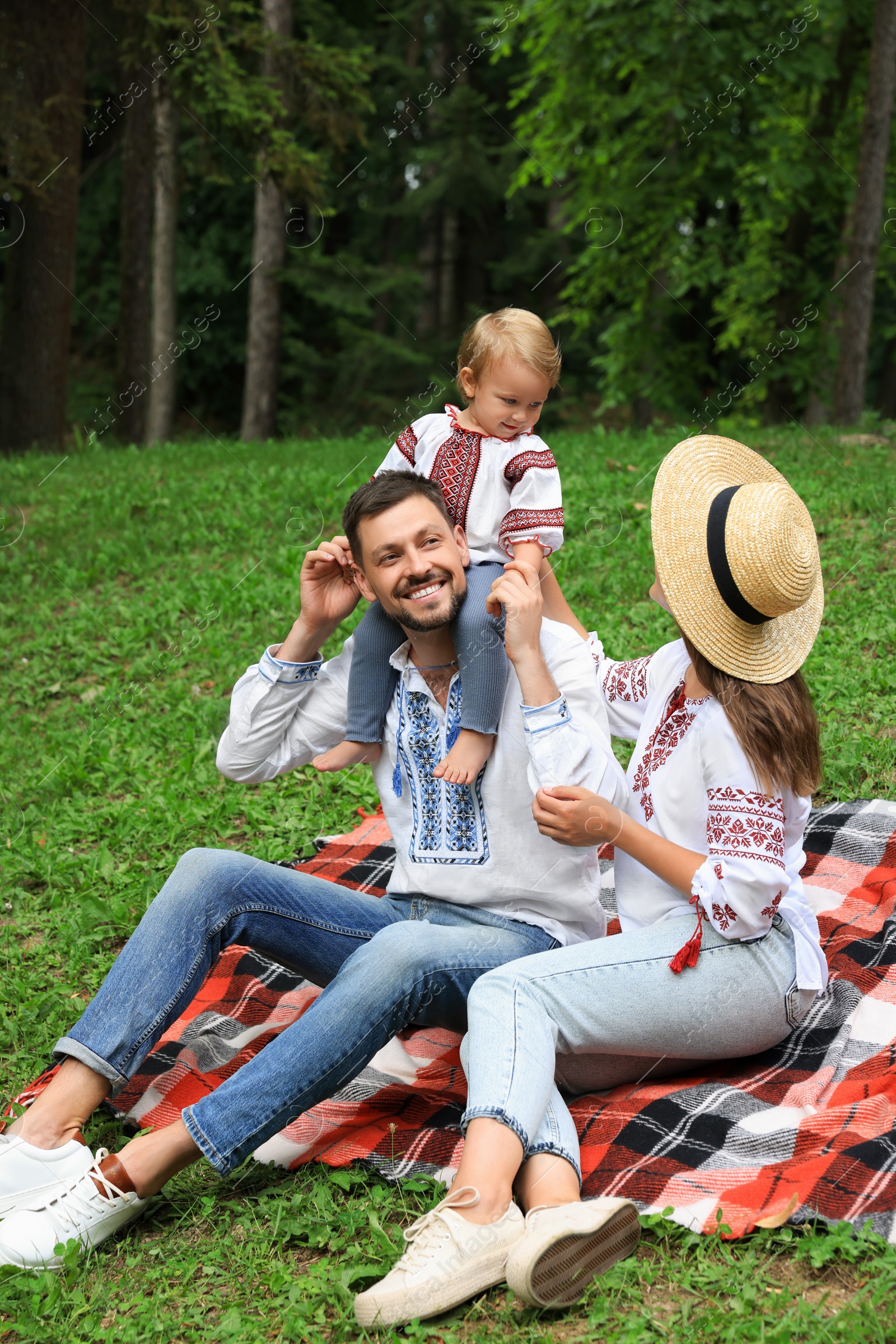 Photo of Happy family in Ukrainian national clothes on green grass outdoors