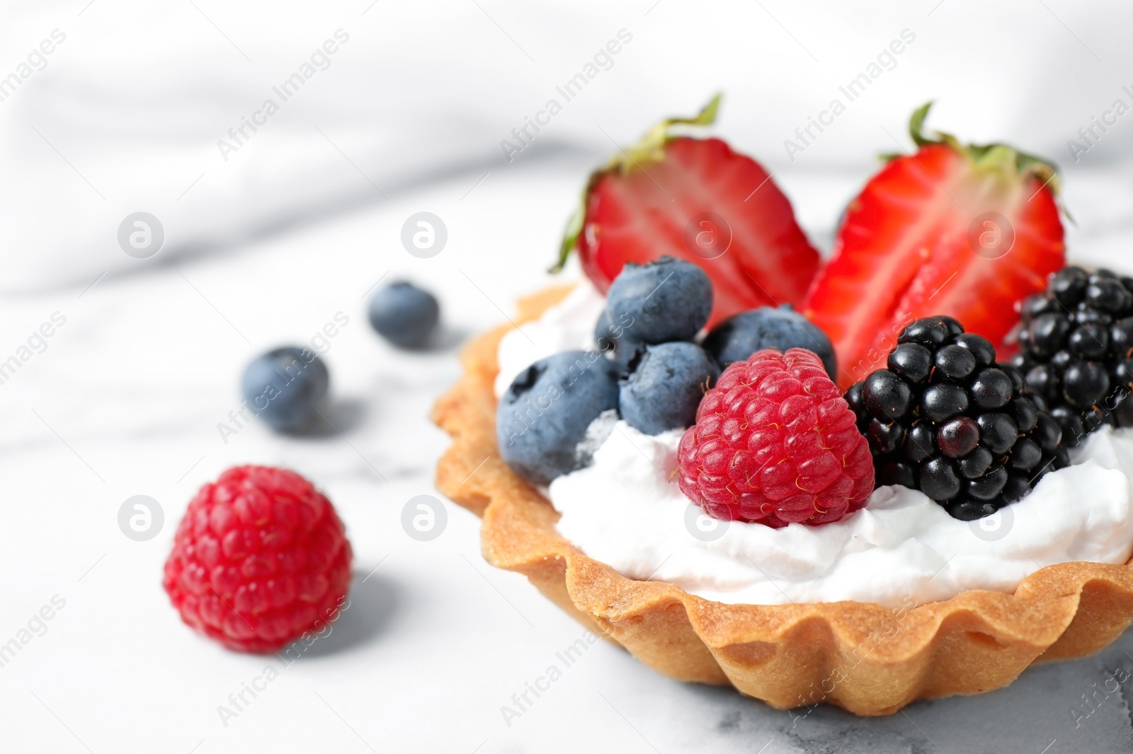 Photo of Tart with different berries on marble table, closeup. Delicious pastries